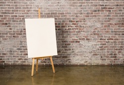 Easel with canvas on a grunge brick wall background