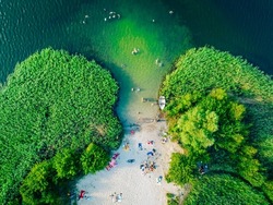 Summer holiday at the green lake. Rest on the beach, leisure time. Aerial view of small hidden beach surrounded by greenery.