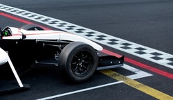 Race start first place concept, formula car nose detail on asphalt racetrack with checkered line