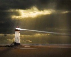 a lighthouse on the welsh coast with light beam and stormy, threatening sky beyond