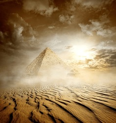 Storm clouds and pyramids in sand desert