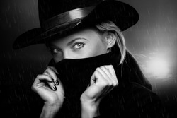 Criminal woman with cowboy hat at twilight under the rain. Natural light and shadows