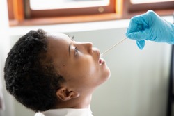 African woman getting throat swab test; concept of universal COVID-19 testing, contact tracing, state quarantine, risk of health care worker, coronavirus detection from saliva specimen by PCR method