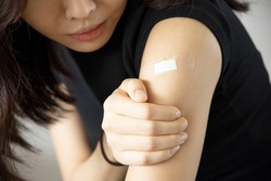 Asian woman receiving getting vaccinated immunity with bandage on her upper arm, concept of innoculation, vaccination, side effects of vaccine