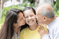 Lovely Asian three generation family with grandfather and mother kissing teen girl, concept of family togetherness