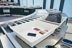 Airport security check. Containers with personal belongings (passport, smart phone, wallet, keys) before x-ray control. 