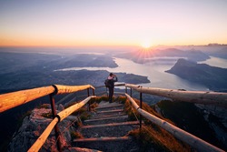 Man photographing landscape with lake and mountains at beautiful sunrise. View from Mount Pilatus, Lucerne, Switzerland