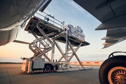 Preparation before flight. Loading of cargo containers to airplane at airport.