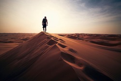 Desert adventure. Young man walking on sand dune against sunset. Abu Dhabi, United Arab Emirates