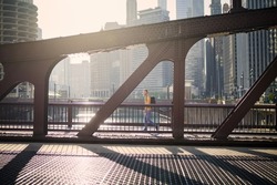 Side view of man on the move while walking on bridge and looking around. City in morning light. 