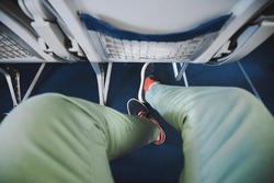 Personal perspective on legroom between seats in airplane. Man resting during flight. 