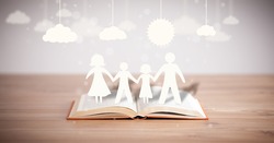 Cardboard figures of the family on opened book. The symbol of unity and happiness