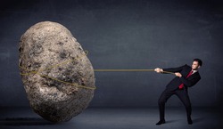 Businessman pulling huge rock with a rope concept on background