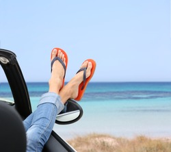 Closeup of woman's feet by convertible car window