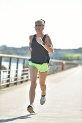 Middle-aged blond woman jogging by the river, citylife
