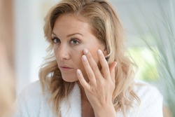 Portrait of attractive blond woman applying anti-aging cream