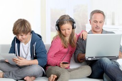 Father and children using electronic devices at home