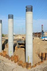 Bridge Construction Project: Dump truck delivers soil for backfilling around concrete columns