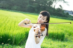 beautiful young woman playing violin in a field