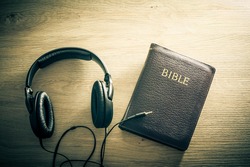 Holy Bible with headphones - symbol of listening to the Word of God.