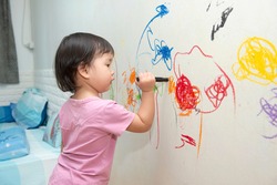 little baby  girl drawing with crayon color on the wall
