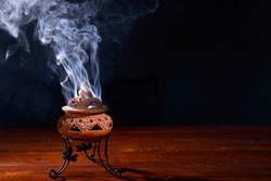 incense burning in an incense burner on the table,with dark background.Religion concept.