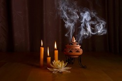 incense burning in an incense burner with candles and beautiful water lily on the table for praying Buddha or Hindu gods to show respect.Religion concept.