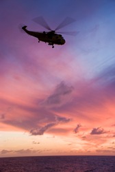 Silhouette of helicopter flying into sunset