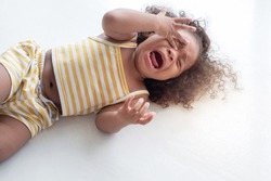  child girl crying and shouting with tantrum lying on the floor at home