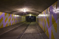 A night-time view of an eerie urban underpass or tunnel.