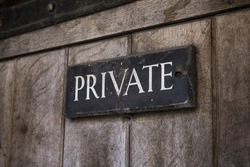 A close-up of a Private sign on an old wooden door.