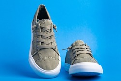 Pair of green casual canvas shoes on a blue background. Space for text.