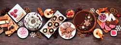 Assorted Christmas holiday desserts and sweets. Top view panoramic table scene over a rustic wood background. Bundt cake, chocolate pie, mincemeat tarts, cookies, fudge and eggnog.