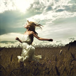 Portrait of romantic woman running across field