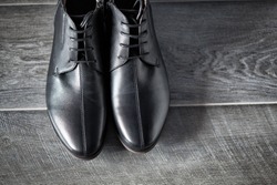 Classic male black leather shoes on wooden background