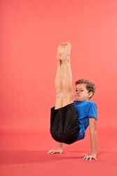 Adorable boy doing yoga exercise against red background