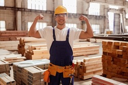 Cheerful male builder demonstrating his muscular arms