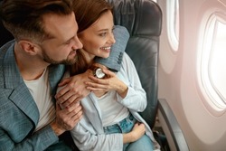 Happy couple in love looking out the window in airplane
