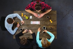 Top view creative photo of friends sitting at dark wooden vintage table. Friends having fun while playing cards