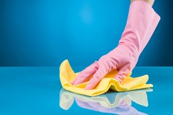 hand with rubber glove cleaning surface with microfiber cloth