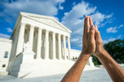 Hands held together in beseeching prayer standing in front of the US Supreme Court building in Washington DC