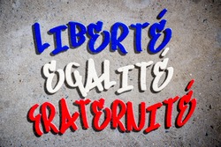 National motto of France (English translation: Liberty, Equality, Fraternity) written in French blue, white, and red tricolor in graffiti text on textured concrete wall