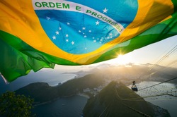 Brazilian flag shines above the golden sunset city skyline at Sugarloaf Pao de Acucar Mountain in Rio de Janeiro Brazil