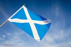 Scottish flag, also known as St Andrew's Cross, flying in bright blue sky