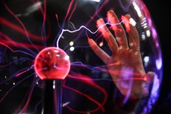 Hand touching with finger electric plasma in glass sphere