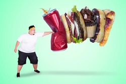 Picture of an Asian obese man wearing sportswear while punching unhealthy foods in green screen background
