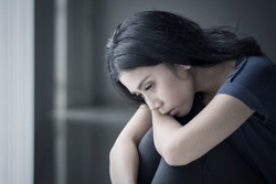 Close up of a sad woman suffering anorexia while sitting in the black background 