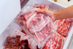 Closeup of hand choosing fresh raw ribs meat in the freezer