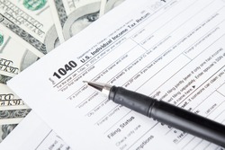 Close up of tax forms with dollar bills and pen