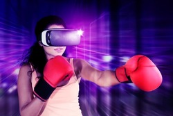 Young woman wearing VR glasses while playing boxing game in the metaverse with cyberspace background